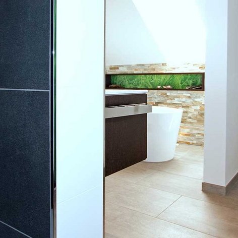 In diesem Badezimmer sind eine elegante Dusche und ein modernes WC zu sehen, umgeben von hellen Fliesen und einem harmonischen Design.