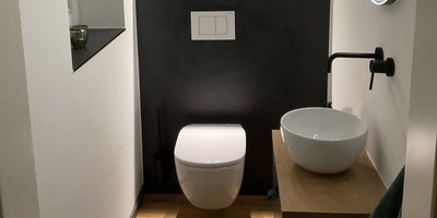 Minimalistische Einrichtung: Stilvolles WC und Waschbecken Ein elegantes Waschbecken und ein modernes WC sind in einem gut beleuchteten, minimalistischen Badezimmer angeordnet.