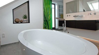 Die freistehende Badewanne im Badezimmer wird von einer modernen Einrichtung und einer großen Fensterfront umgeben.