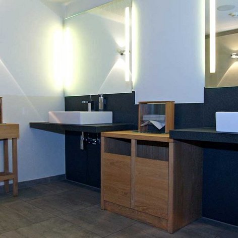 Der Raum zeigt eine harmonische Kombination aus Holz und Stein, mit einem großen Spiegel und sanfter Beleuchtung.