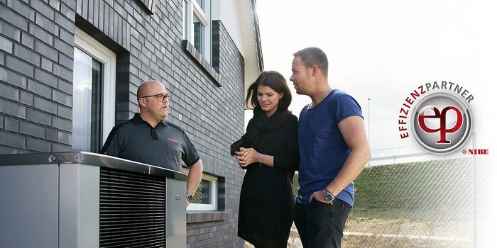 Das Paar hört aufmerksam zu, während der Fachmann Informationen über die Heiztechnik an einem sonnigen Tag vermittelt.