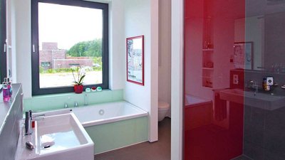 Ein modernes Badezimmer mit großen Fenstern, einer Badewanne und einem Waschbecken, umgeben von stilvollen Accessoires.