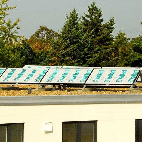 Auf dem Dach eines modernen Gebäudes sind mehrere Solarpanels installiert, umweltfreundliche Energieerzeugung im Fokus.